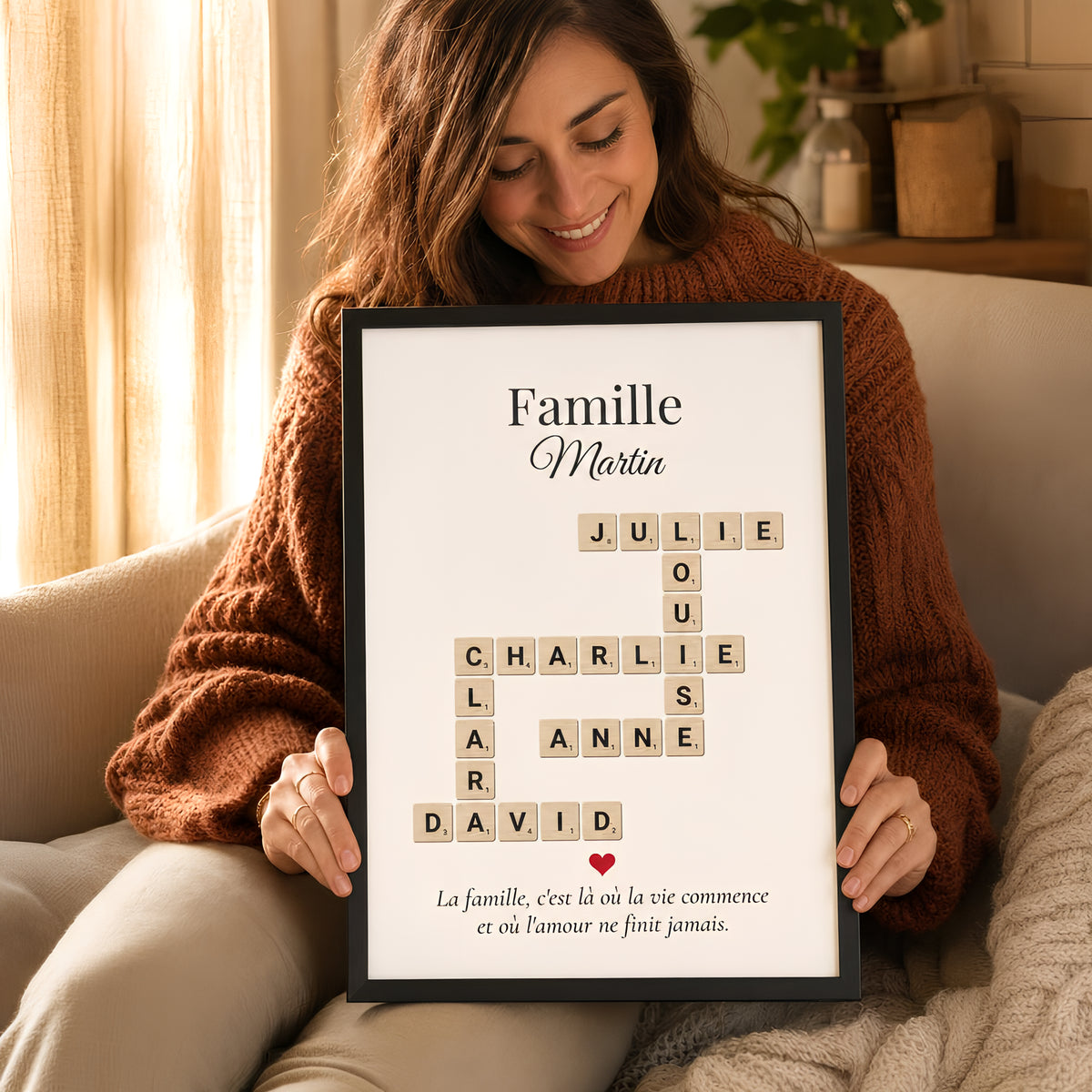 Femme tenant une affiche Scrabble famille personnalisée encadrée avec les prénoms en mots croisés